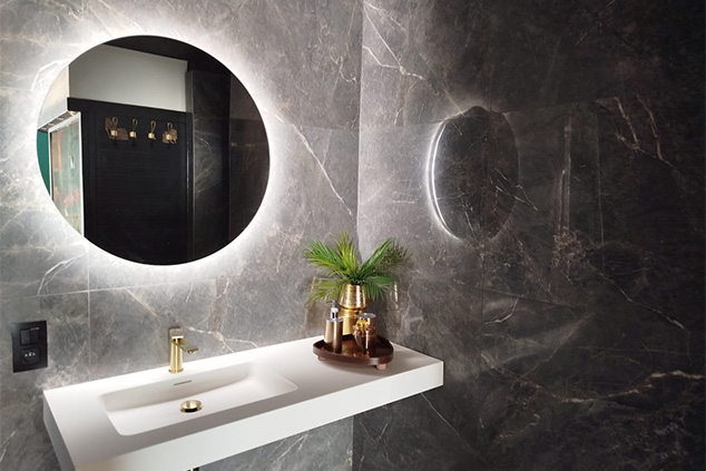 Lavabo blanc suspendu avec robinet doré, miroir rond rétroéclairé et décoration élégante dans une suite privative
