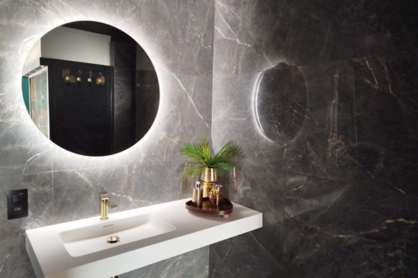 Lavabo blanc suspendu avec robinet doré, miroir rond rétroéclairé et décoration élégante dans une suite privative
