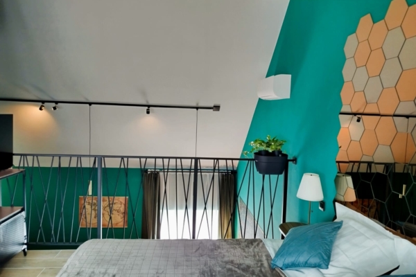Lit confortable avec coussins bleus et décoration murale moderne dans une suite privative