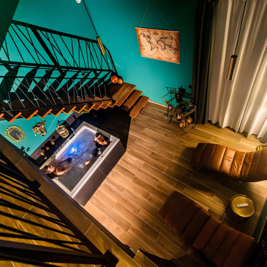 Vue en plongée sur un bain à remous et un espace détente avec chaises longues, dans une ambiance chic et chaleureuse